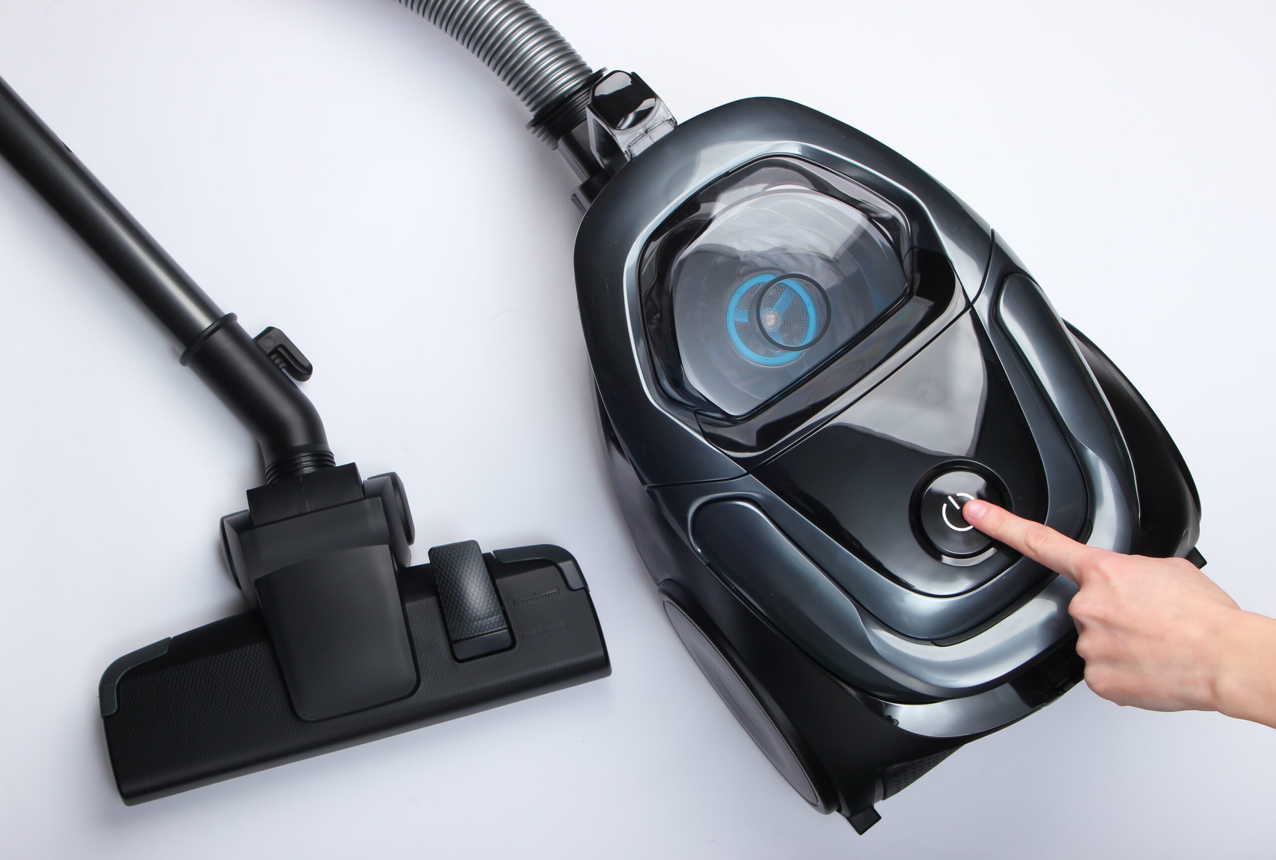 female-hand-turns-vacuum-cleaner-white-surface-min